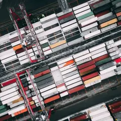 Widok z lotu ptaka na terminal kontenerowy, gdzie trwa **tranzyt co to** jest widoczne w postaci rzędów kolorowych kontenerów i dźwigów.