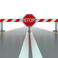Bariera z napisem STOP blokuje drogę, symbolizując zakazy ruchu ciężarówek w Europie.