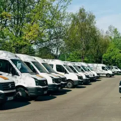 Rząd białych busów zaparkowanych na zewnątrz. Idealne do pracy z własnym busem i transportu.