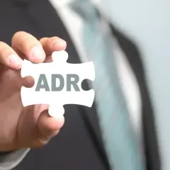 Dłoń trzyma element układanki z napisem ADR. To klucz do zrozumienia podstawowych pytań i odpowiedzi w testach ADR.