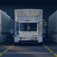 Trzy białe ciężarówki stojące obok siebie. Na jednej z nich widnieje napis "cargolog". W niedzielę obowiązuje zakaz jazdy.