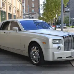 Biały Rolls-Royce, idealny na umowę transportu okazjonalnego, lśni na tle miejskiej architektury.