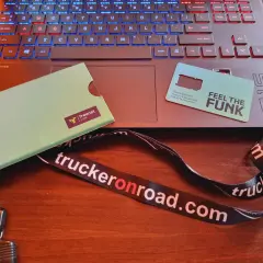 Karta SIM "Feel the Funk" i klucze na smyczy "truckeronroad.com" leżą obok laptopa. Czas na pauzę 45h bez karty w tachografie.