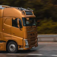 Złoty ciągnik siodłowy z naczepą jedzie drogą. Prawo przewozowe reguluje takie transporty, zapewniając bezpieczeństwo i płynność ruchu.