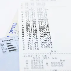 Druk na kartę kierowcy z danymi o czasie i dystansie. Widoczna karta kierowcy i wydruk z tachografu.