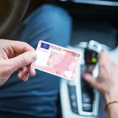 Osoba trzyma polskie prawo jazdy. W tle widać wnętrze samochodu, co sugeruje, że może to być dokument potrzebny do prowadzenia pojazdu, gdy posiada się prawo jazdy spoza Unii Europejskiej.