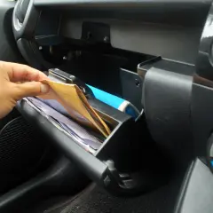 Ręka sięga do schowka po dokumenty. Kierowca musi mieć przy sobie dowód rejestracyjny, polisę OC i prawo jazdy.