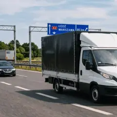 Biała furgonetka i inne pojazdy na autostradzie A2, kierujące się do Łodzi i Warszawy. Przepisy transportowe regulują ruch tych pojazdów.