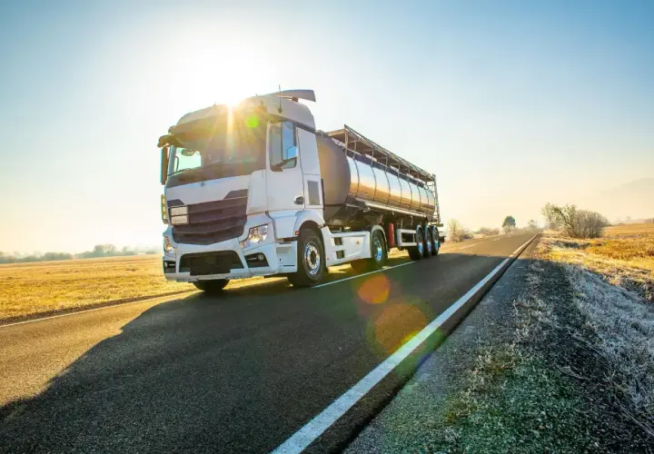 Ciężarówka cysterna na drodze o wschodzie słońca. Bezpieczny transport to podstawa, dlatego warto pamiętać o darmowe testy adr.