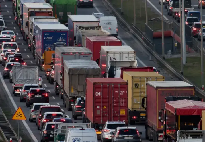 Korki na autostradzie w Polsce. Długi sznur samochodów i ciężarówek, widoczne znaki ostrzegawcze.