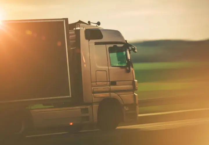 Ciężarówka w ruchu, symbolizująca profesjonalizm i sprawność w transporcie, gdzie kluczowe jest użyczenie certyfikatu kompetencji zawodowych.