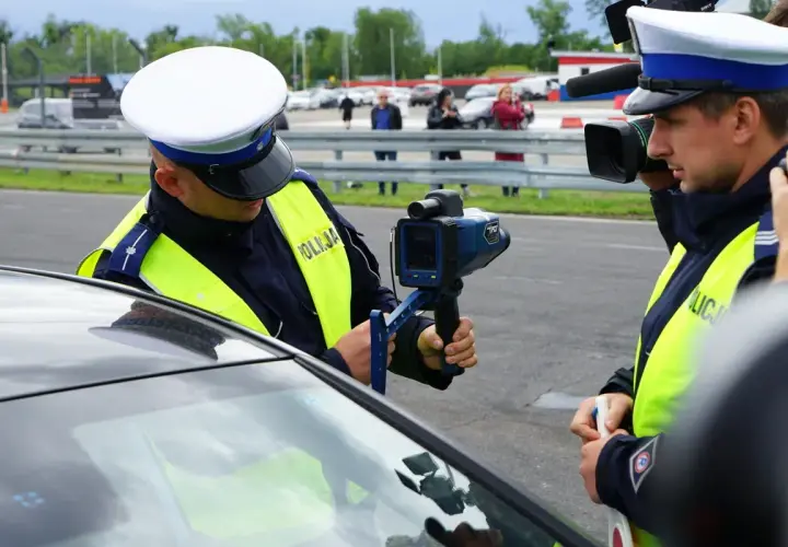 Policjant mierzy prędkość, grozi zabrane prawo jazdy za prędkość. Inny funkcjonariusz filmuje akcję.