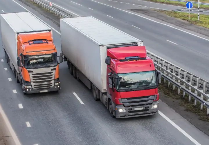 Dwa ciężkie samochody ciężarowe jadące autostradą, przestrzegając dopuszczalny nacisk na oś w Polsce.