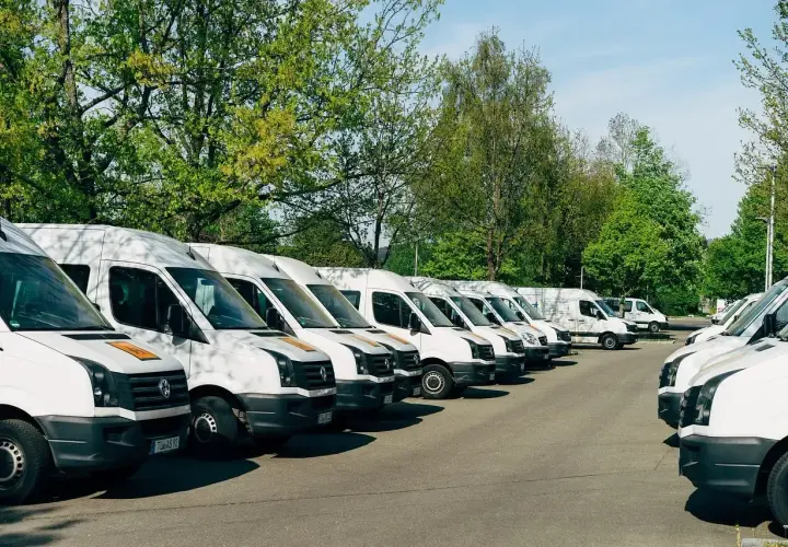 Rząd białych busów zaparkowanych na zewnątrz. Idealne do pracy z własnym busem i transportu.