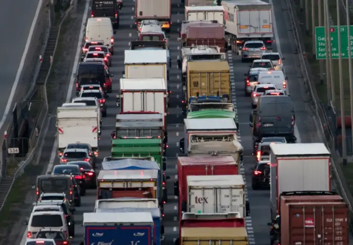 Korek na autostradzie, mnóstwo ciężarówek i samochodów. Widać znaki informujące o zakazie jazdy ciężarówek.