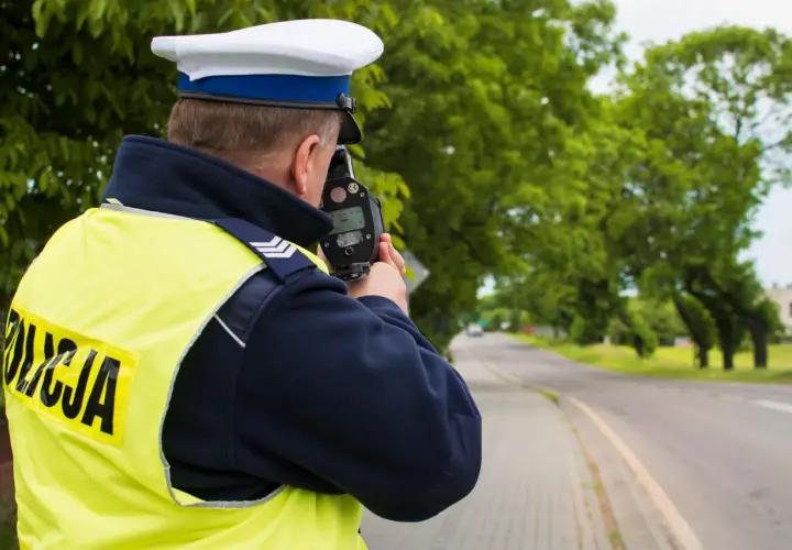 Policjant mierzy prędkość. Kierowco, uważaj na przekroczenie prędkości o 20 w terenie zabudowanym, bo możesz dostać mandat.