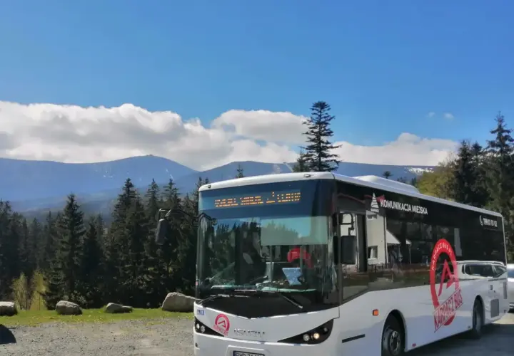 Biały autobus komunikacji miejskiej "Karpacz Bus" na tle gór i lasu. Idealny transport busem na górskie wycieczki.