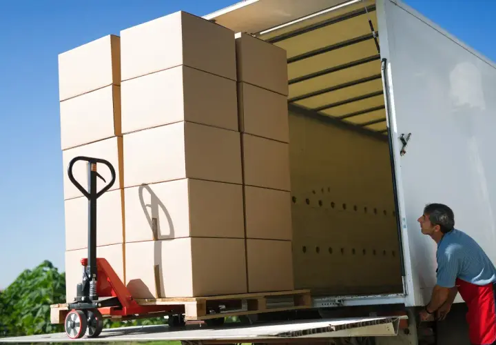 Pracownik ładuje paletę z kartonami do ciężarówki. Efektywny transport drobnicowy Polska.