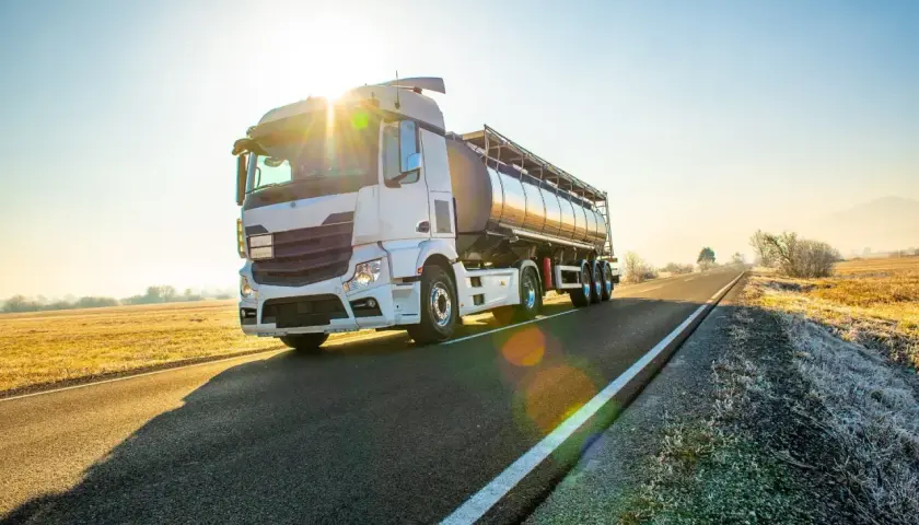 Ciężarówka cysterna na drodze o wschodzie słońca. Bezpieczny transport to podstawa, dlatego warto pamiętać o darmowe testy adr.