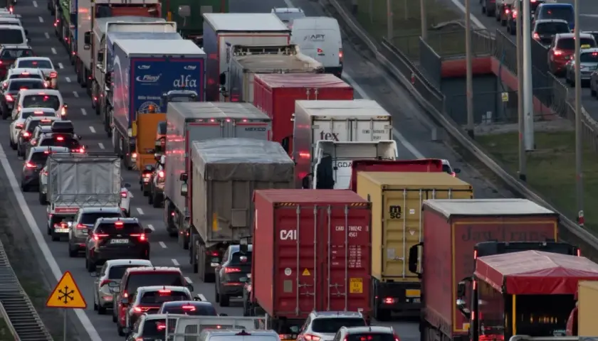 Korki na autostradzie w Polsce. Długi sznur samochodów i ciężarówek, widoczne znaki ostrzegawcze.