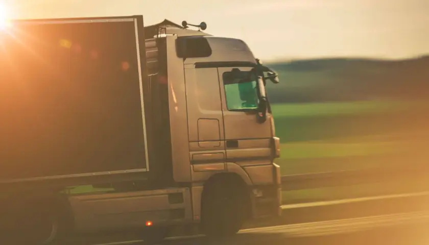 Ciężarówka w ruchu, symbolizująca profesjonalizm i sprawność w transporcie, gdzie kluczowe jest użyczenie certyfikatu kompetencji zawodowych.