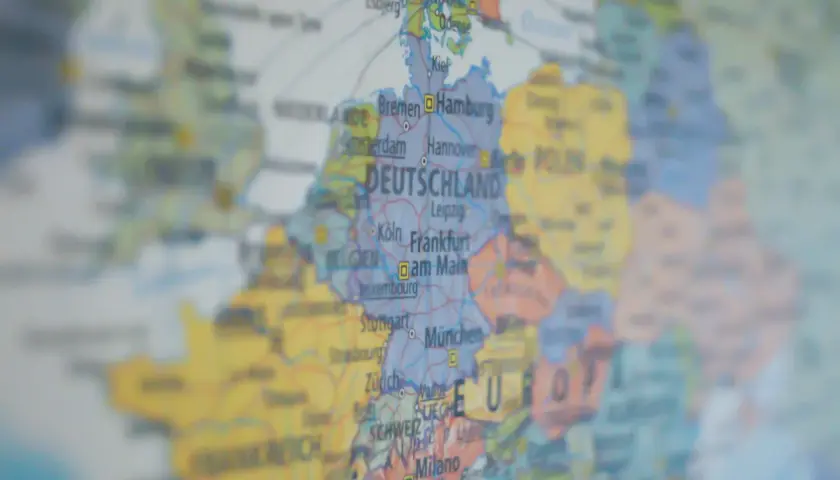 Mapa Europy z zaznaczoną DEUTSCHLAND. Widać miasta takie jak Hamburg, Frankfurt, Monachium. W tle widoczne są landy niemieckie, zakazy podróżowania w Europie.