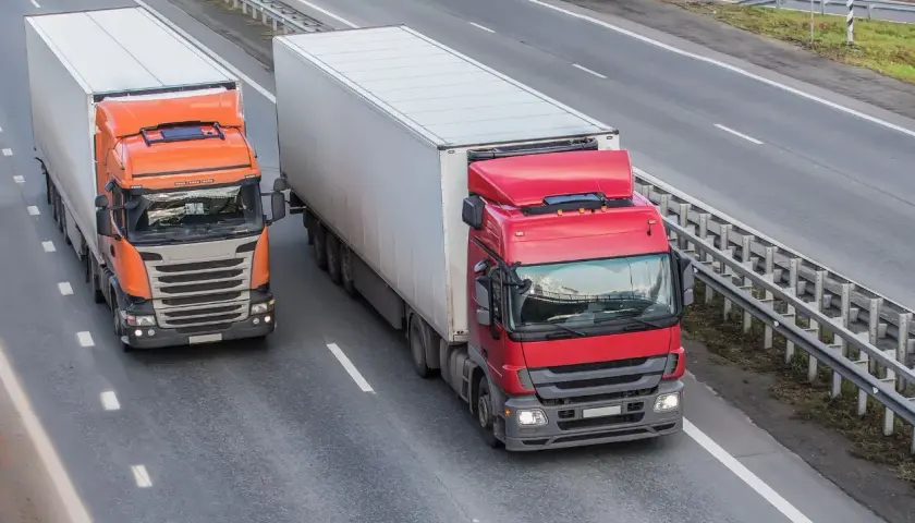 Dwa ciężkie samochody ciężarowe jadące autostradą, przestrzegając dopuszczalny nacisk na oś w Polsce.