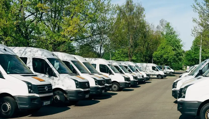 Rząd białych busów zaparkowanych na zewnątrz. Idealne do pracy z własnym busem i transportu.