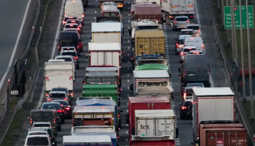 Korek na autostradzie, mnóstwo ciężarówek i samochodów. Widać znaki informujące o zakazie jazdy ciężarówek.