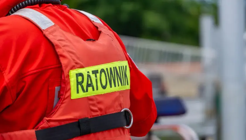 Ratownik w czerwonym stroju, z napisem "RATOWNIK" na kamizelce. Może to być sytuacja, gdy ktoś próbuje kierować ruchem bez uprawnień, a ratownik jest na miejscu.