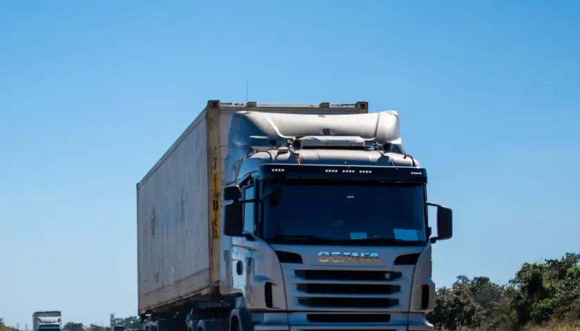 Ciężarówka Scania przewozi kontener. Zastanawiasz się, ile za kilometr busem po Polsce?