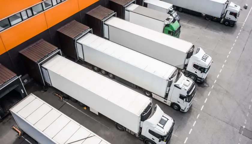 Ciężarówki czekają na załadunek przy magazynie. Logistyka między Francją a Polską kwitnie, zapewniając płynny transport towarów.