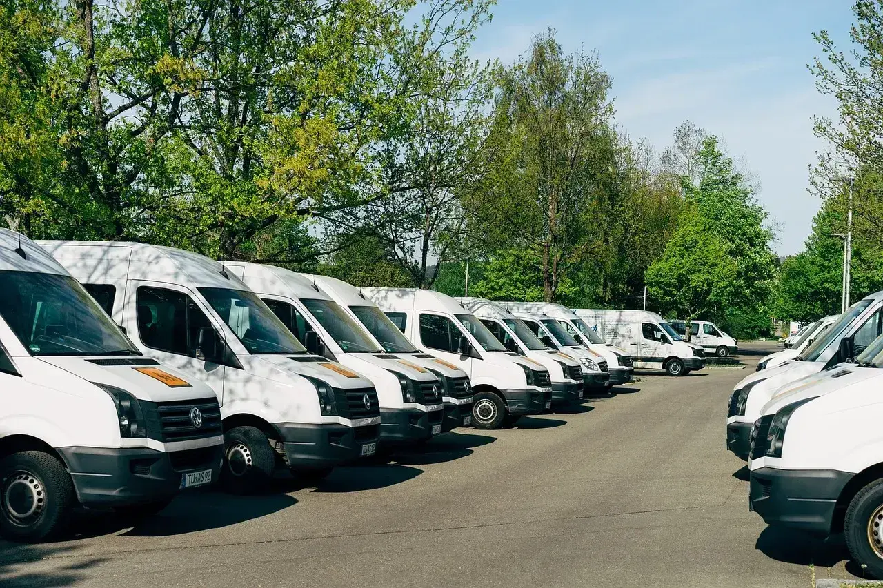 Rząd białych busów zaparkowanych na zewnątrz. Idealne do pracy z własnym busem i transportu.