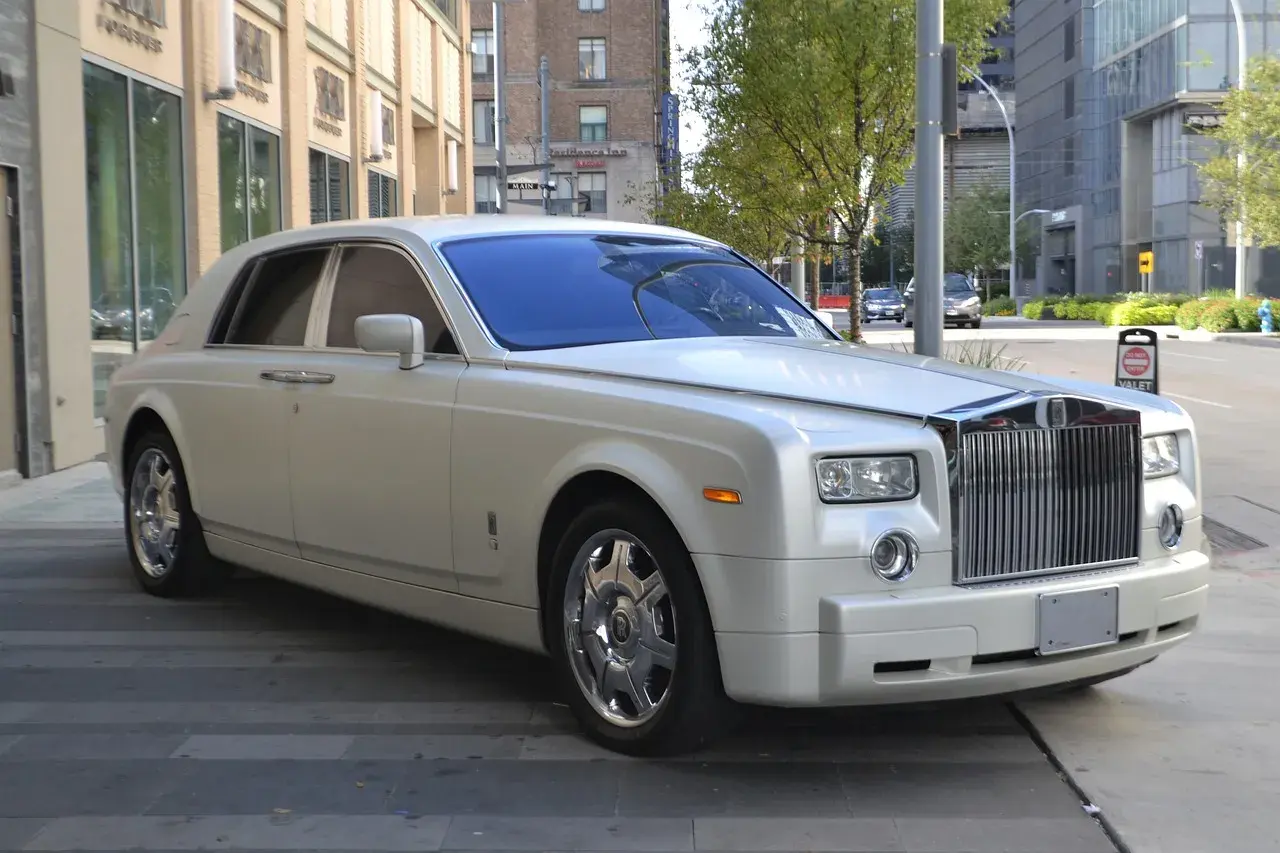 Biały Rolls-Royce, idealny na umowę transportu okazjonalnego, lśni na tle miejskiej architektury.