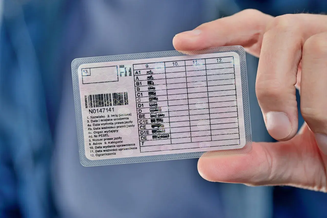 Dłoń trzyma polskie prawo jazdy. Widoczna jest data ważności uprawnienia, co pokazuje, ile jest ważne prawo jazdy.