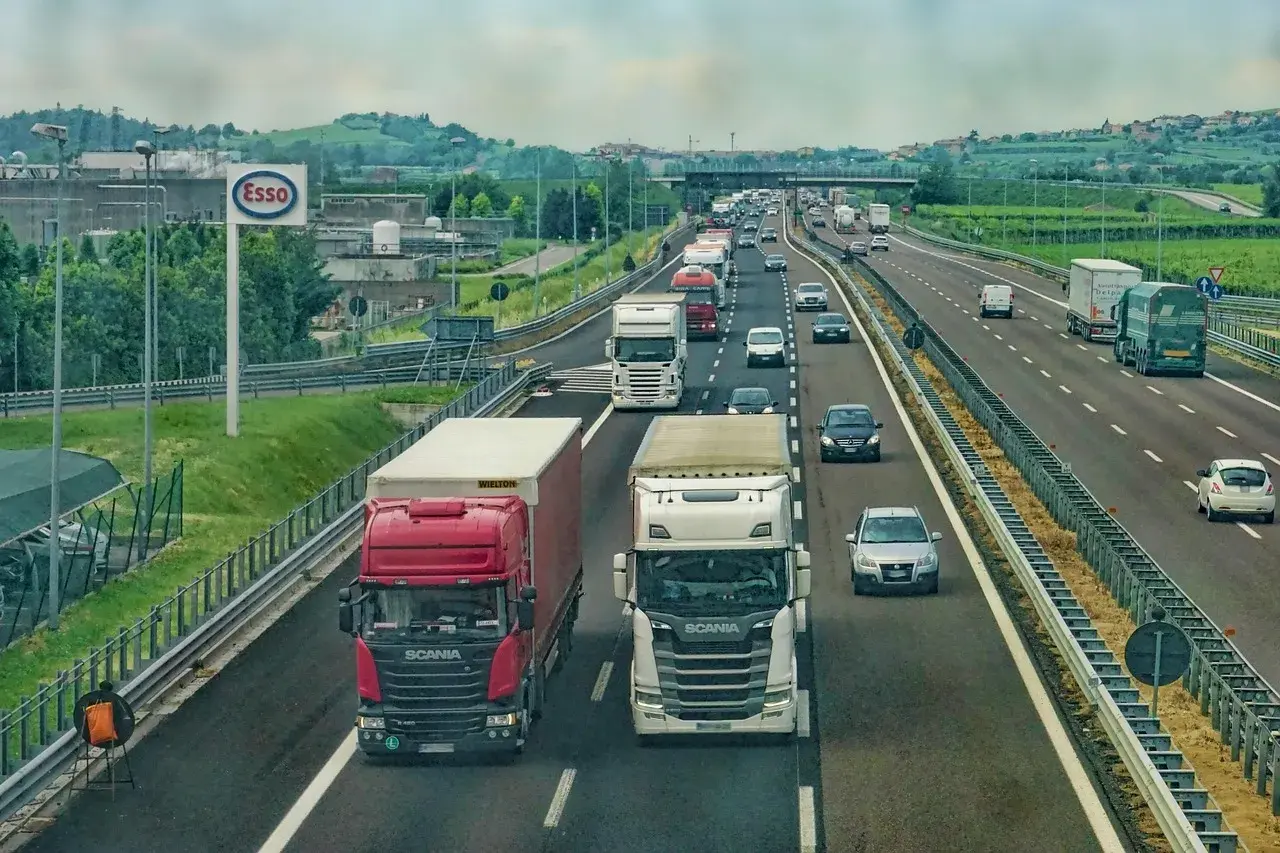 Autostrada pełna ciężarówek, samochodów i znak Esso. To obrazek pokazujący, kabotaż co to jest – transport towarów w obrębie jednego kraju przez zagraniczną firmę.
