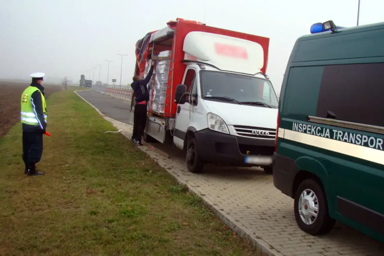 Kontrola samochodu ciężarowego do 3,5 tony. Policjant w kamizelce odblaskowej i inspektor transportu przy białej ciężarówce.