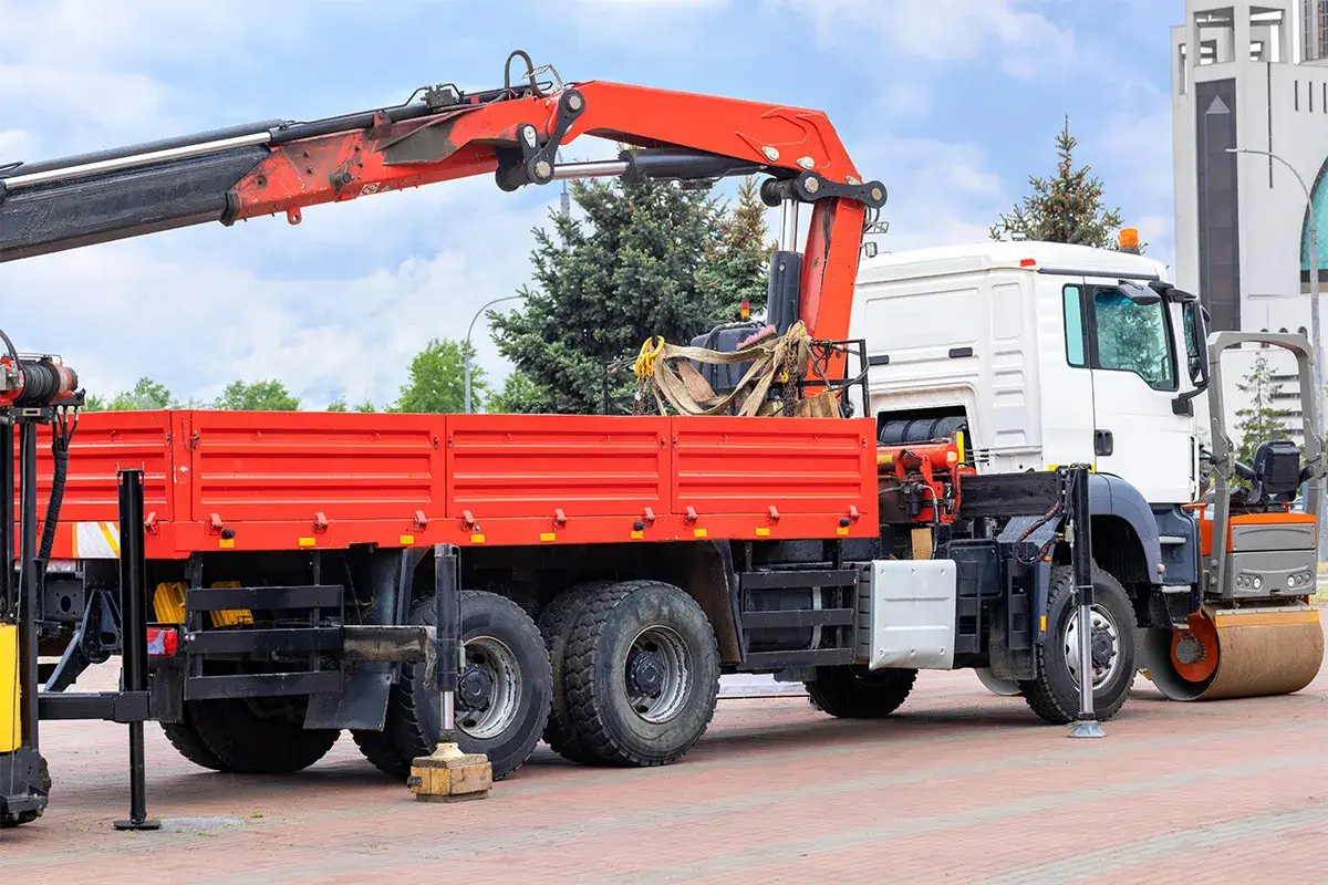 Ciężar&oacute;wka z HDS gotowa do pracy. Pomarańczowy dźwig uniesiony, czerwona skrzynia ładunkowa czeka na załadunek.