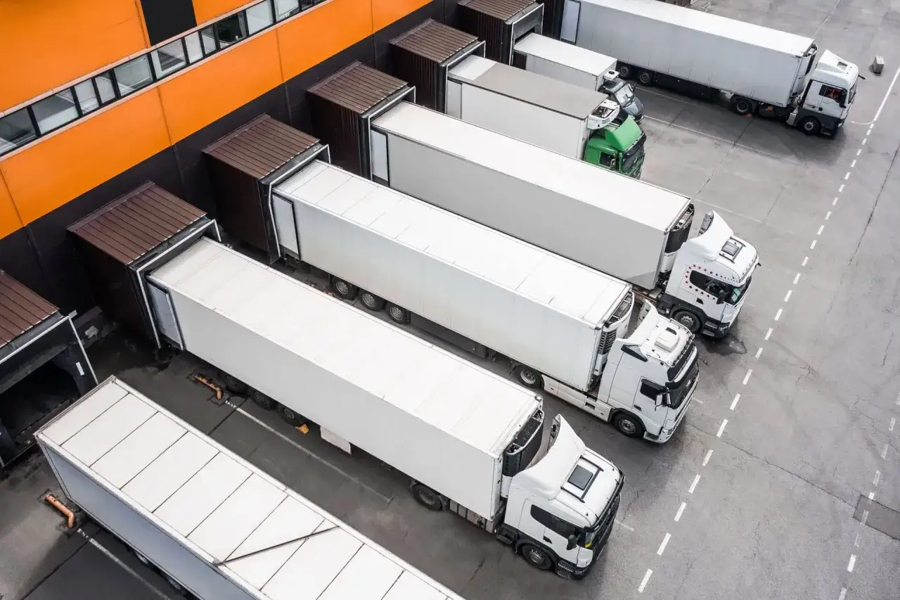 Ciężarówki czekają na załadunek przy magazynie. Logistyka między Francją a Polską kwitnie, zapewniając płynny transport towarów.