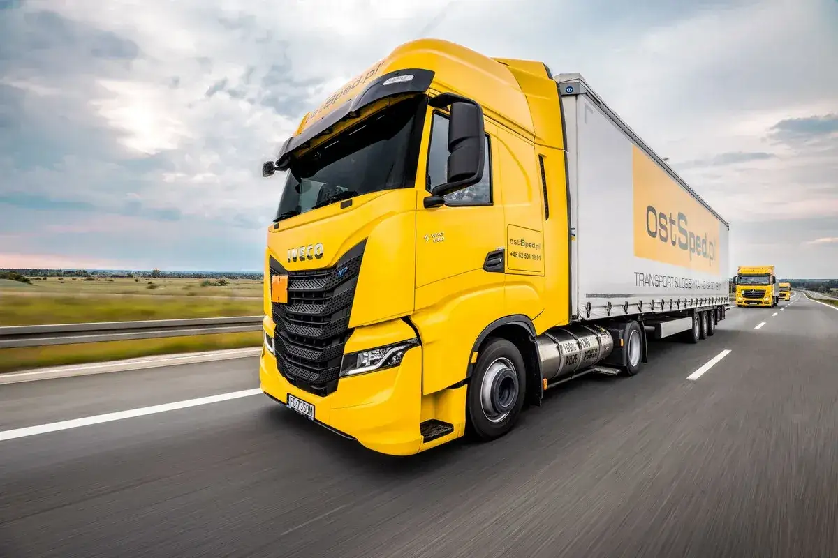 Żółte ciężarówki Iveco i Mercedes jadą autostradą. Praca c+e to ich codzienne wyzwanie.